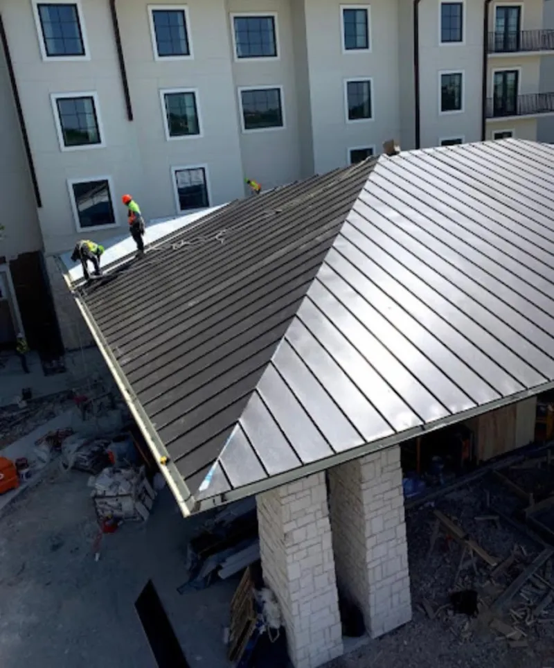 Crew installing standing seam metal roof panels on a commercial project in Cuyahoga Falls